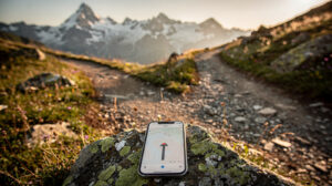 Wanderweg in den Alpen, der sich in zwei Pfade teilt, davor ein Smartphone mit Offline-Karte